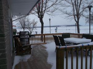 a patio with a grill and chairs and snow on a fence at Haileybury Beach Motel in Haileybury