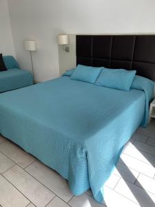 a blue bed with a black headboard and blue sheets at Zara in Corigliano Calabro +4 photos