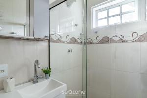 ein Badezimmer mit Dusche, Waschbecken und Spiegel in der Unterkunft Casa Espaçosa 300m da Praia do Peró - VVP0027 in Peró + 17 Fotos