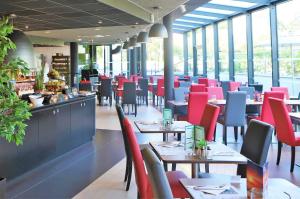 a restaurant with tables and red chairs and windows at Campanile PRIME - Toulouse Sud Balma Cité de l'Espace in Toulouse