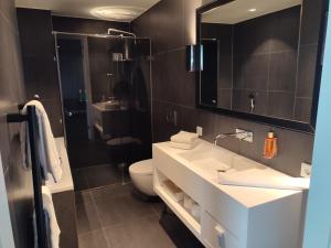 a bathroom with a sink and a toilet and a mirror at B-aparthotel Kennedy in The Hague +47 photos