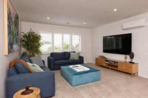 a living room with two blue couches and a flat screen tv at Making Memories - Ocean Grove in Ocean Grove