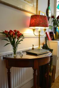 a table with a lamp and a vase of flowers on it at Knightsrest in Burnham on Sea