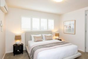 a white bedroom with a large bed with two lamps at Making Memories - Ocean Grove in Ocean Grove