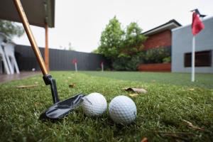 two golf balls and a bat on the grass at Making Memories - Ocean Grove in Ocean Grove