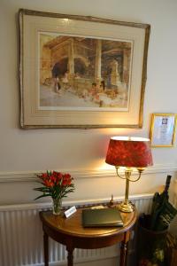 a table with a lamp and a picture on the wall at Knightsrest in Burnham on Sea