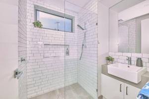 a white bathroom with a shower and a sink at Grove Hideaway - Peaceful 2 bed townhouse in Ocean Grove +17 photos