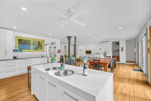 a kitchen with white cabinets and a dining room with a table at Aireys Bush Retreat in Aireys Inlet