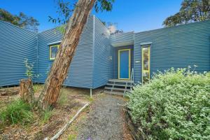 a blue house with a tree in front of it at Aireys Bush Retreat in Aireys Inlet