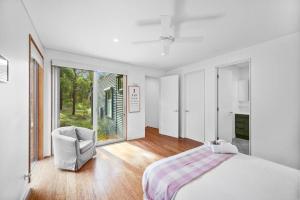 a white bedroom with a bed and a chair at Aireys Bush Retreat in Aireys Inlet