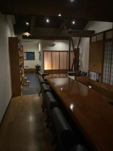 a room with a long wooden table and chairs at 泊まれるbarたにかぜ in Tokimata