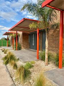 a building with orange pillars and a palm tree at Posada Patagonia San Juan in Pocito