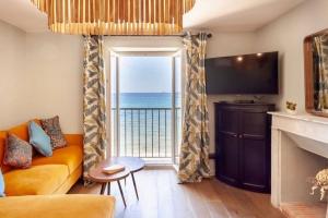 a living room with a couch and a large window at Appartement Bord de plage Vue mer in Brando
