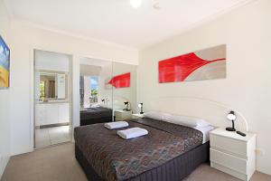 - une chambre avec un grand lit et un miroir dans l'établissement Blue Waters Apartments, à Gold Coast