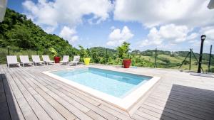 ein Swimmingpool auf einer Holzterrasse mit Stühlen in der Unterkunft Séjour Glycéria: Villa Canne à Sucre in Le Marin