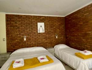 a bedroom with two beds and a brick wall at Posada Patagonia San Juan in Pocito +15 photos