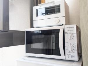 a white microwave oven sitting on top of a counter at 鶴の宿 那覇-国際通りまで950mの便利な立地-1棟貸切 in Naha