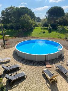a large swimming pool with lounge chairs and a table at Maison à la campagne avec PISCINE et JACUZZI in Buanes