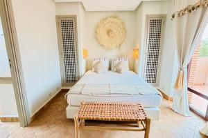 a bedroom with a bed and a bench in it at Chic Villa - Samanah Golf, Pool, Sunset Views in Tameslouht