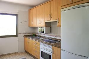 Una cocina con gabinetes de madera, un fregadero y un refrigerador. en House Loma Gomera in San Sebastian, en San Sebastián de la Gomera