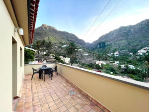 a balcony with a table and chairs and mountains at Penthouse Las Palmeras in Valle Gran Rey +3 photos