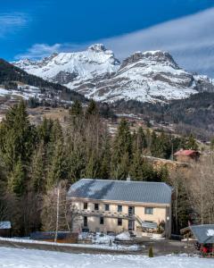 a building with snow covered mountains in the background at Le Moulin des Olirics in Sallanches