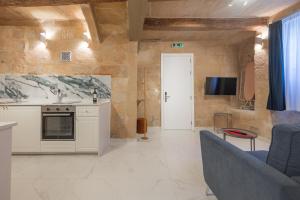 une cuisine et un salon avec un canapé et une télévision dans l'établissement Palazzo Stella Ground Floor Studio by Vallettastay, à La Valette