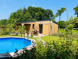 a house with a swimming pool in a yard at Gîte cottage à 5 min de Dinan avec bain nordique "Côté Jardin" in Bobital