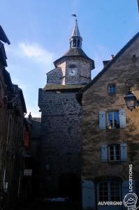 ein altes Gebäude mit einem Uhrturm darüber in der Unterkunft Gîte des Remparts in Besse-et-Saint-Anastaise + 3 Fotos