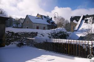 einen schneebedeckten Hof mit einem Zaun und Häusern in der Unterkunft Gîte des Remparts in Besse-et-Saint-Anastaise