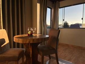 a table with two wine glasses and two chairs at Pousada Serra Geral in Cambara do Sul
