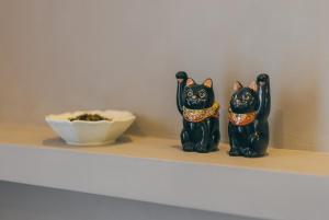 two black cats sitting on a shelf with a bowl at Lane in Niigata