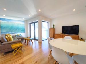 a living room with a couch a table and a tv at Sandpiper Cottages in Newquay