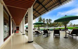 a patio with tables and chairs and umbrellas at Lake Palace Trivandrum in Vettutura