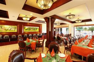 een restaurant met tafels en stoelen met oranje servetten bij Lake Palace Trivandrum in Vettutura