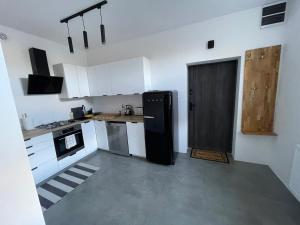 a kitchen with a black refrigerator and white cabinets at Apartament Nowomiejska in Wałcz