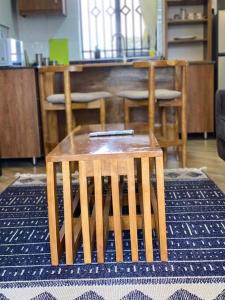 a wooden stool sitting on a rug in a room at Firefly Hill- a Cozy, one bedroom apartment in Kampala