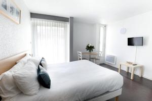 a bedroom with a white bed and a television at Hotel Thermes Les Ecureuils-Dax in Dax