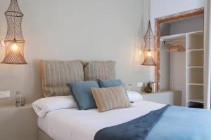 a bedroom with a bed with white sheets and blue pillows at Hostal Boutique Sa Nansa in Tossa de Mar +23 photos
