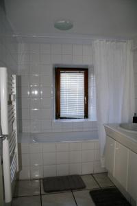 ein weißes Bad mit einer Badewanne und einem Fenster in der Unterkunft Apartment Au Calme in Munster