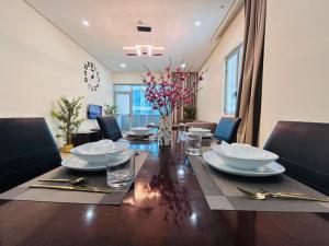 a dining room with a table with plates and glasses at Aspire Tower-Two Bedroom Palm Stay in Manama