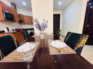 a dining room table with chairs and a vase of flowers at Aspire Tower - One Bedroom Solo Haven Juffair in Manama