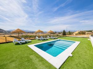 a swimming pool on a lawn with chairs and umbrellas at Cubo's La Casa Azul in Villafranco de Guadalhorce