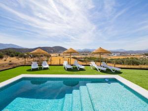 a swimming pool with chairs and umbrellas on a lawn at Cubo's La Casa Azul in Villafranco de Guadalhorce