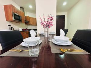 una mesa de comedor con platos, vasos y flores. en Aspire Tower-One Bedroom Blissful Nest, en Manama