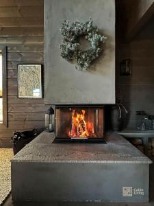 a fireplace with a wreath on top of it at Modern cabin at Høgevarde panoramic view, fireplace and EV station in Granheim +47 photos