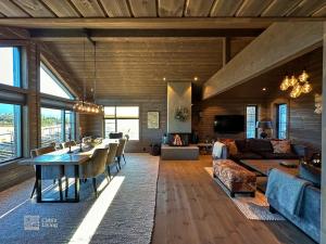 a large living room with a table and a couch at Modern cabin at Høgevarde panoramic view, fireplace and EV station in Granheim