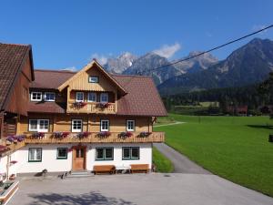 dom z zielonym polem i górami w tle w obiekcie Haslehnerhof w mieście Ramsau am Dachstein