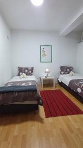 a bedroom with two beds and a red rug at Petrograd in Bitola