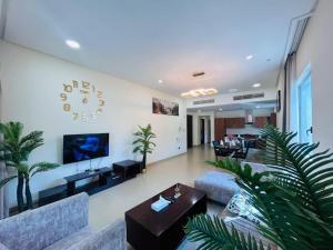 a living room with couches and a clock on the wall at Aspire Tower-Two Bedroom Urban Haven Juffair in Manama